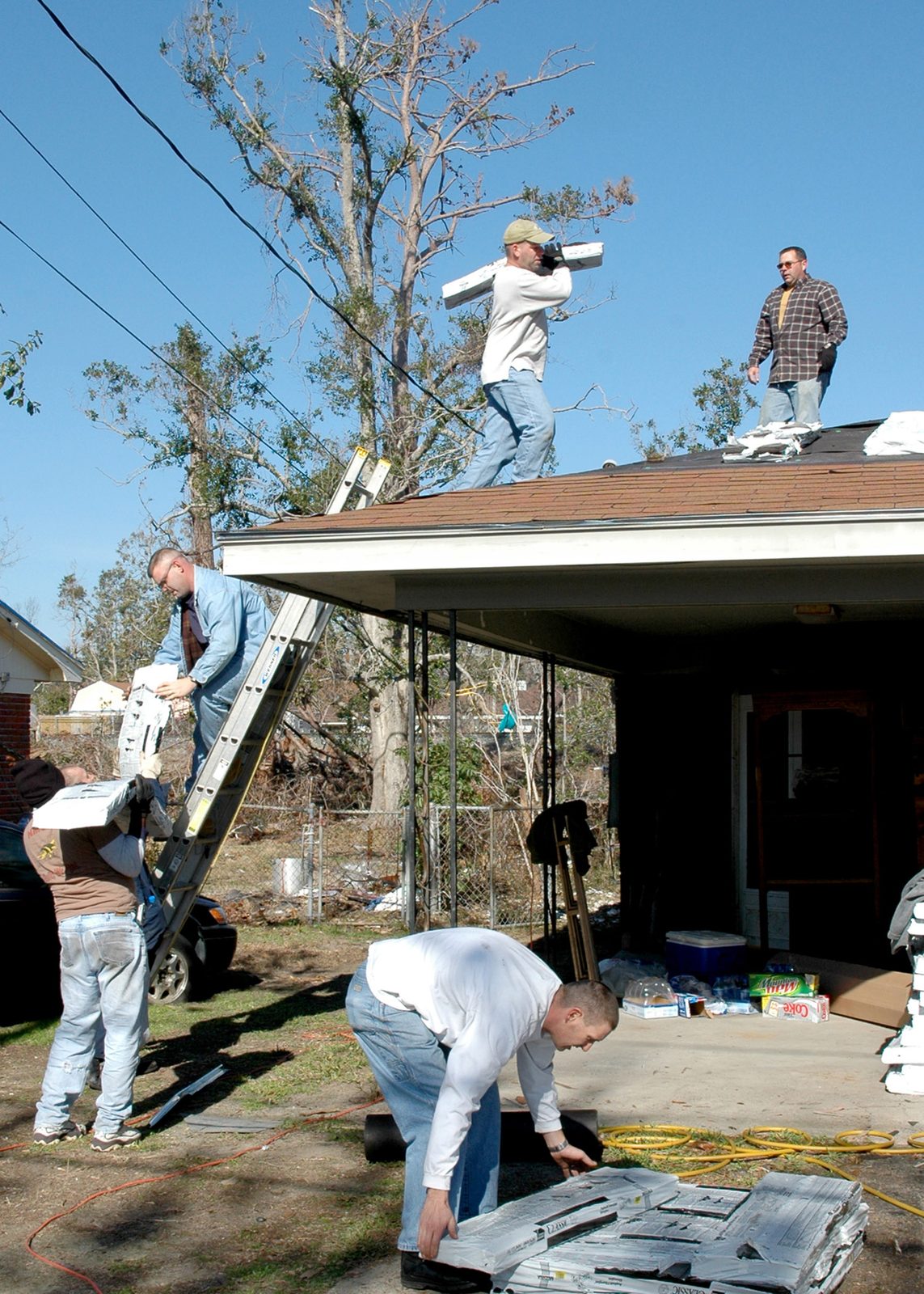 Crews repairing a roof on a home damaged by a hurricane